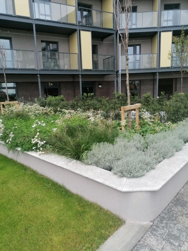 modern apartment complex with a landscaped garden and a brick sidewalk